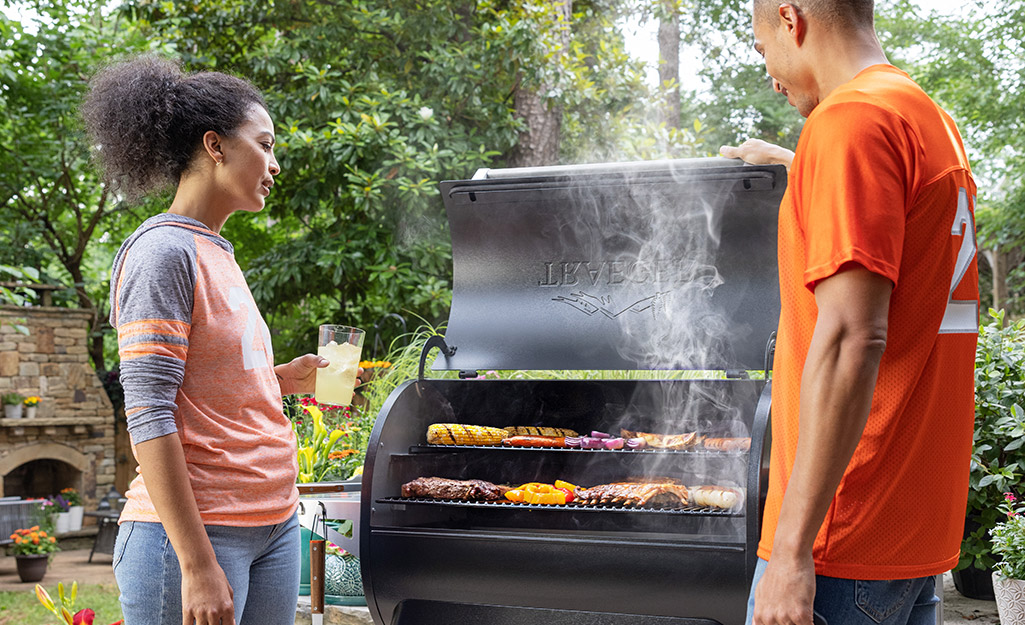 Two people in football fan gear grill food. Two people in football fan gear grill food.