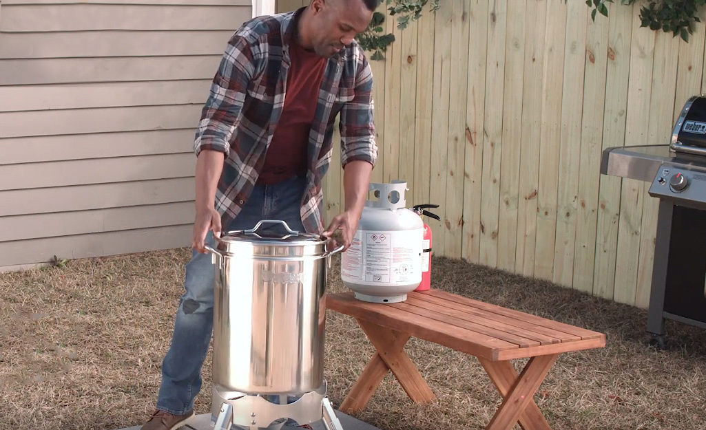 A person setting up a turkey fryer outside.