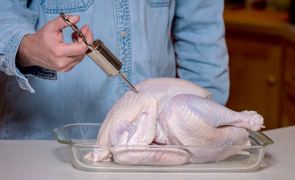 A person injecting a turkey to prepare it for the turkey fryer.