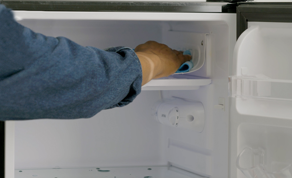 Person cleaning the inside of a fridge.
