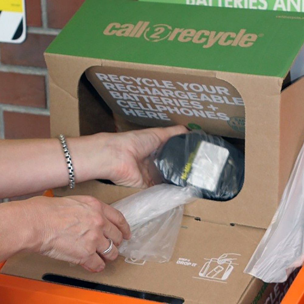 A person puts a battery inside a recycling box.
