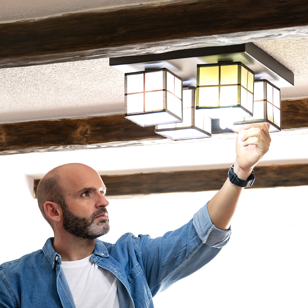 A man changes a lightbulb in a ceiling fixture.