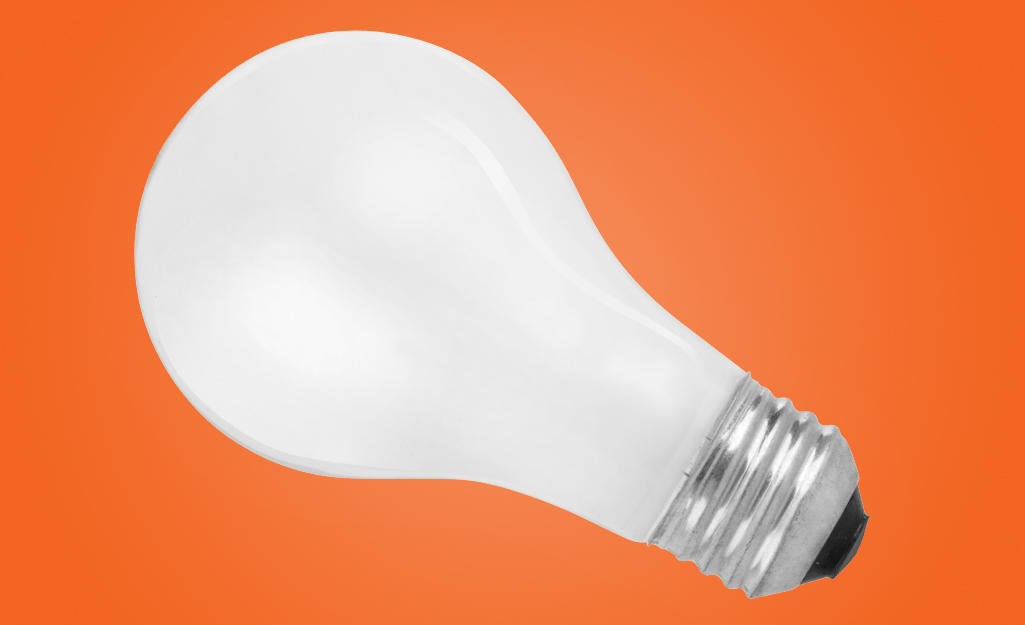 An incandescent lightbulb on an orange background.