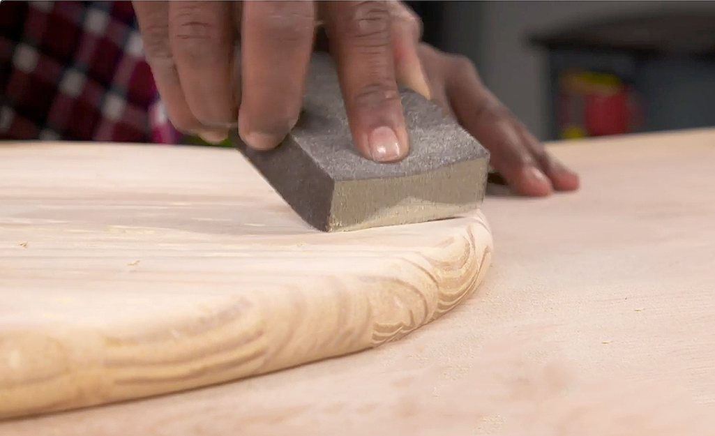 A sanding block is used to distress wood.