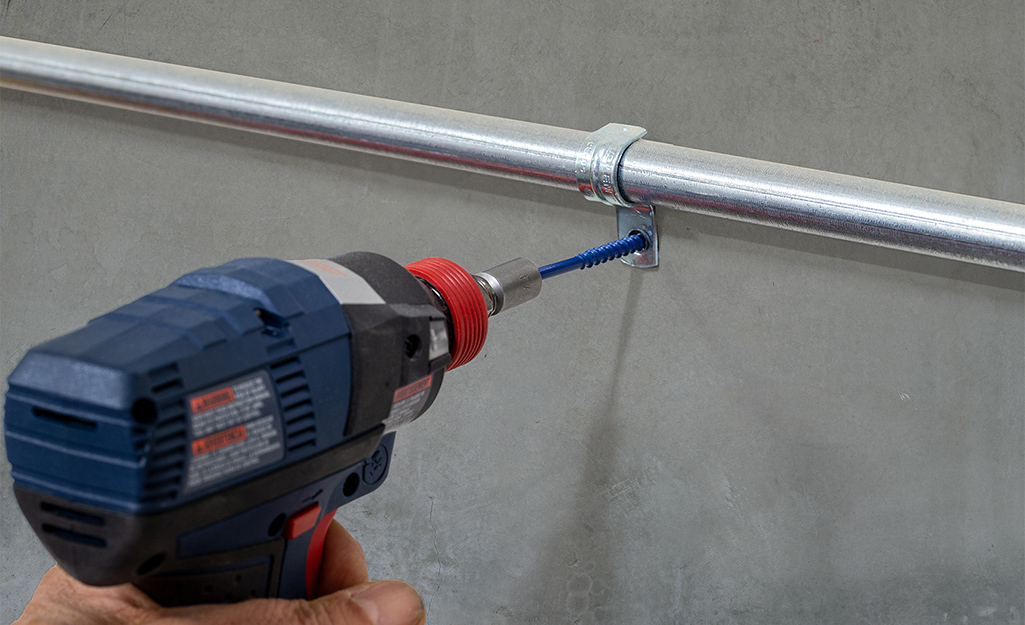 A person drilling an anchor into a wall. 