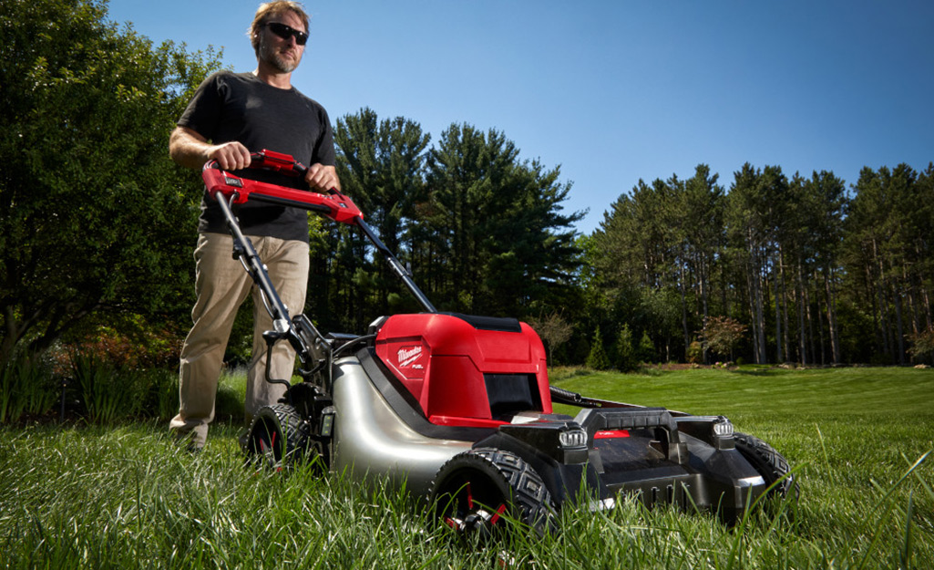 A homeowner mowing a lush lawn.