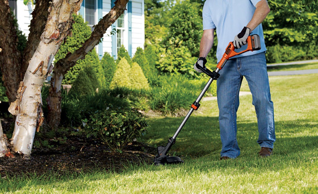 A person using a power edger to trim the grass.