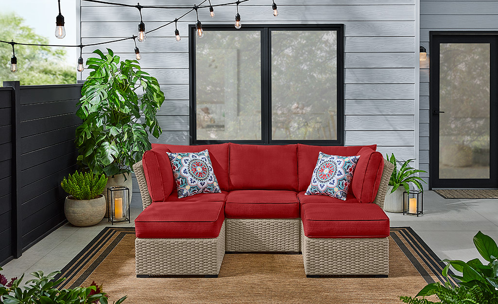 Throw pillows accent a red outdoor sectional sofa on a patio.
