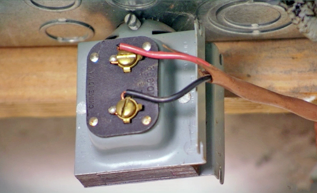 A picture of a doorbell transformer attached to a house rafter beam.
