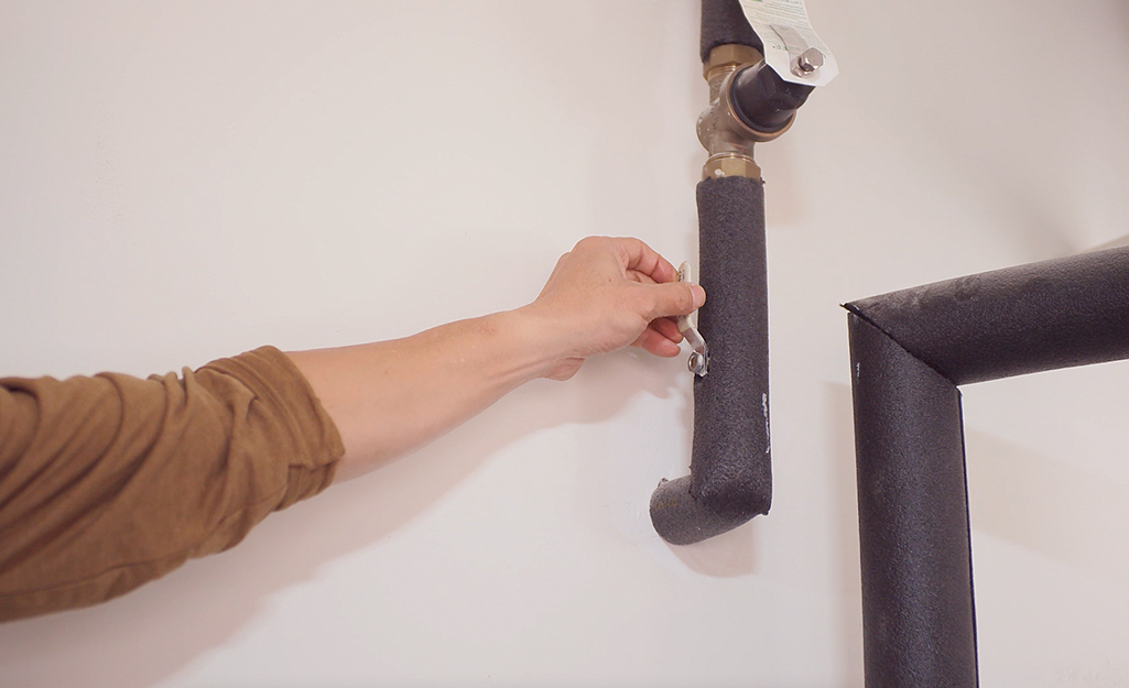 A person turning off a shut-off valve on a home's water main.