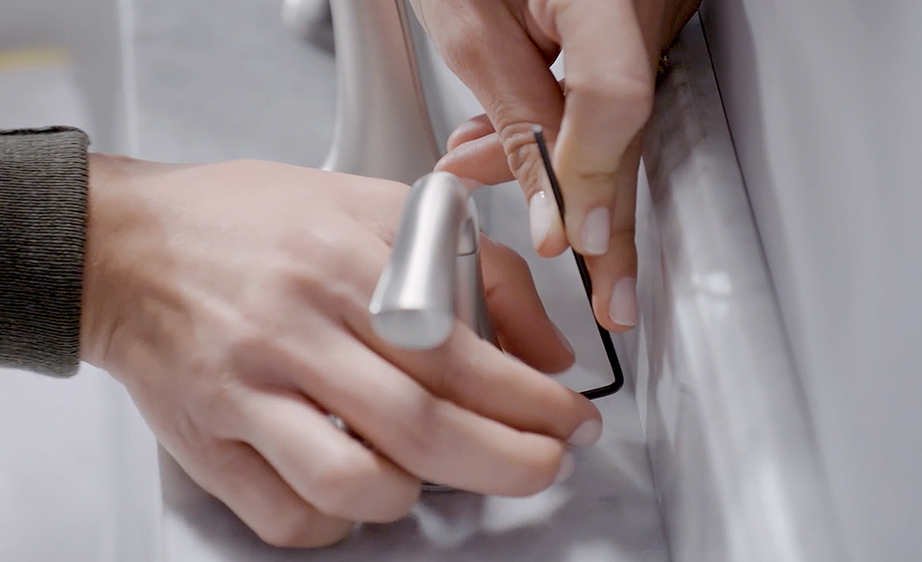 A person uses a hex key to remove the set screw from the handle.