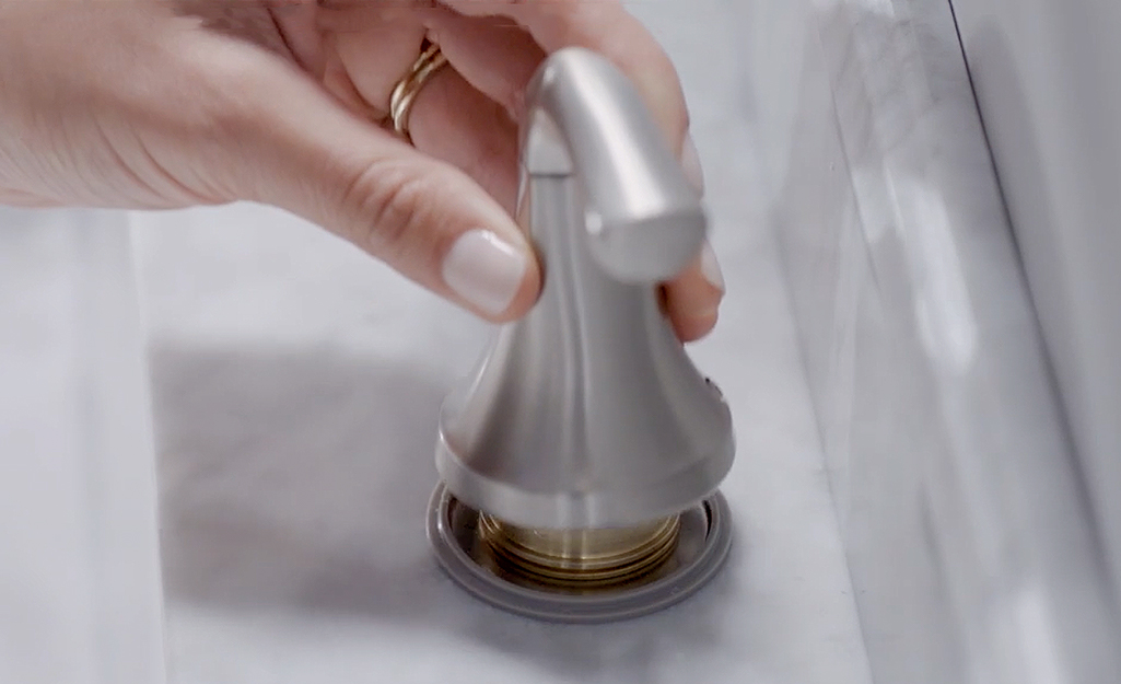 A person reattaches the bathroom sink handle.