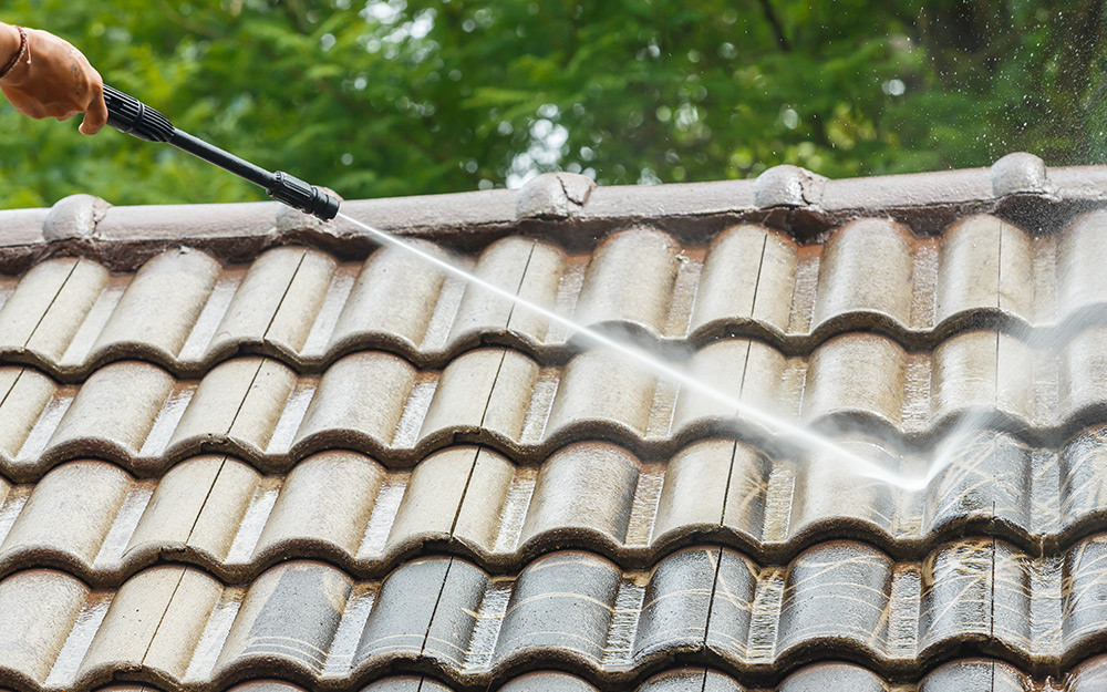 A garden hose is used to spray water on a roof.