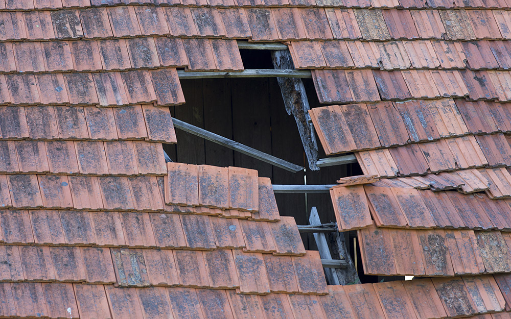 A damaged roof with an exposed hole is in need of repair.