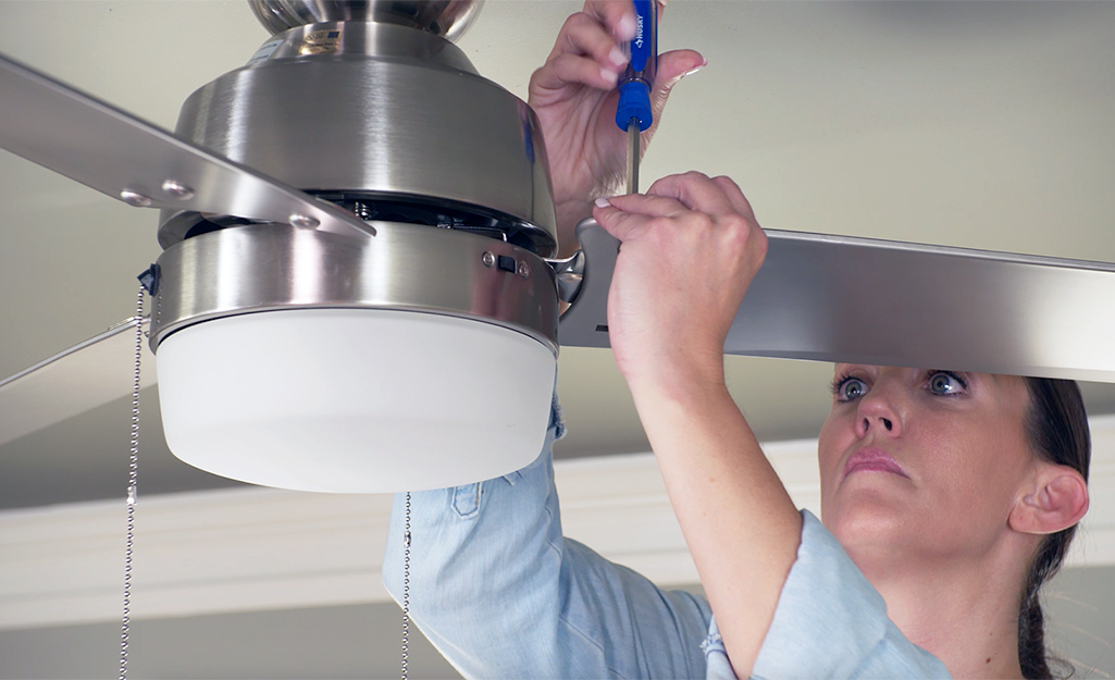 A person adjusting a ceiling fan