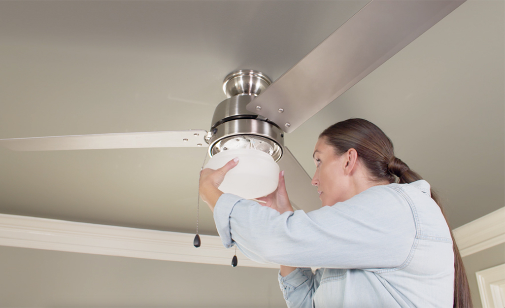 A woman attaching the light on a ceiling fan