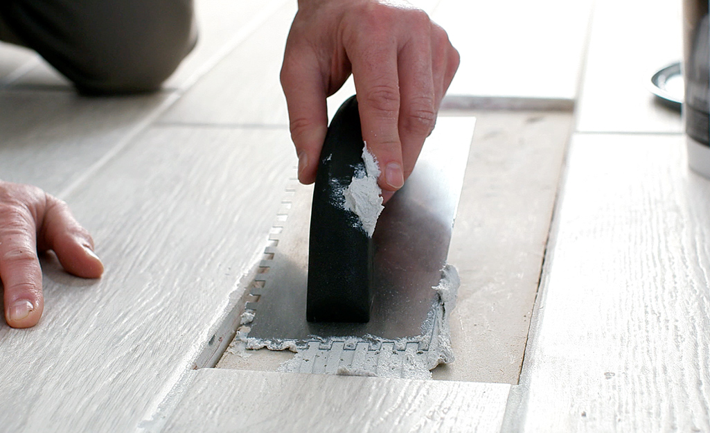 A person applies thin-set mortar in the area the tile will be placed.