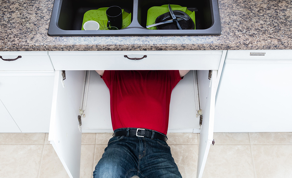 A person working under a sink.