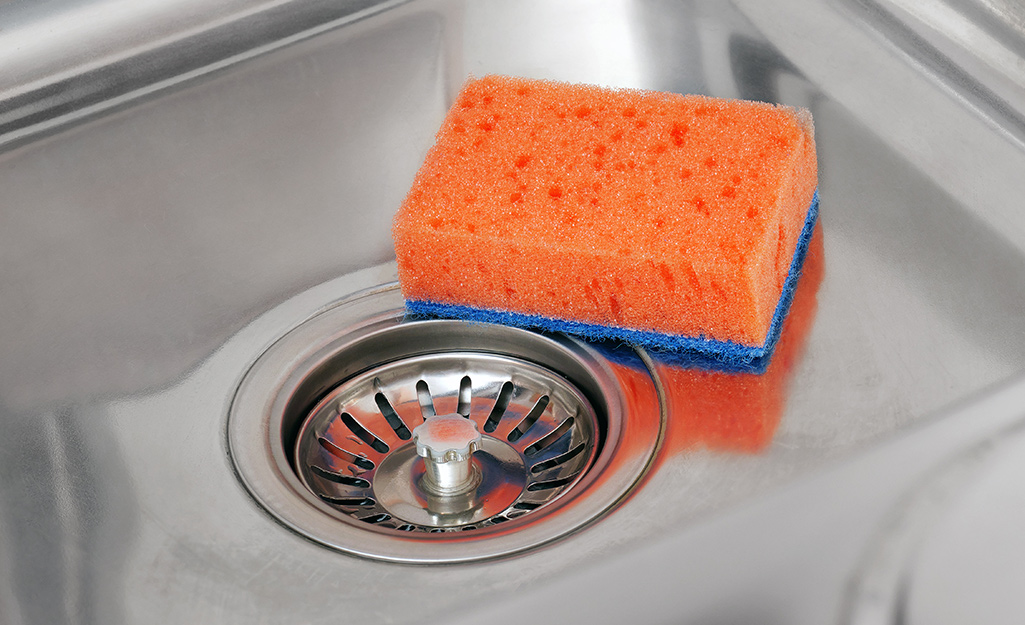 A sponge laying beside a sink strainer.