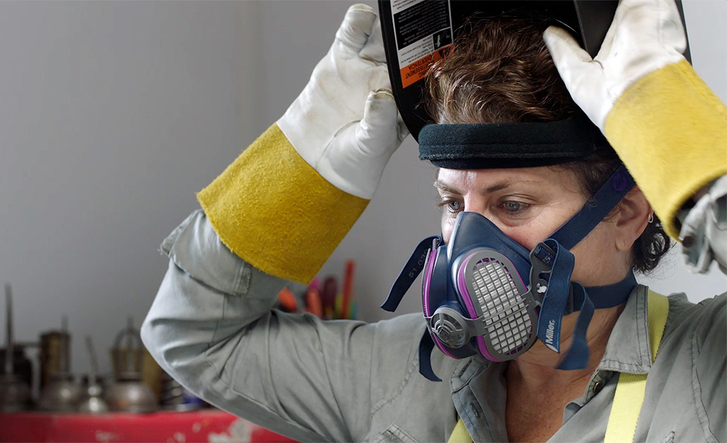 A person puts on safety equipment before welding.