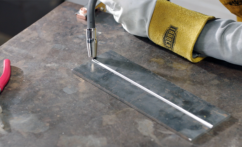 A welder uses the pull technique on metal.