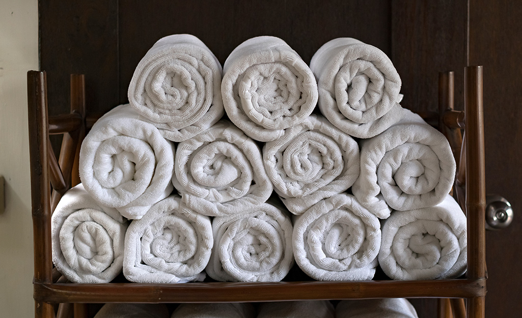 White towels rolled up inside a cabinet.