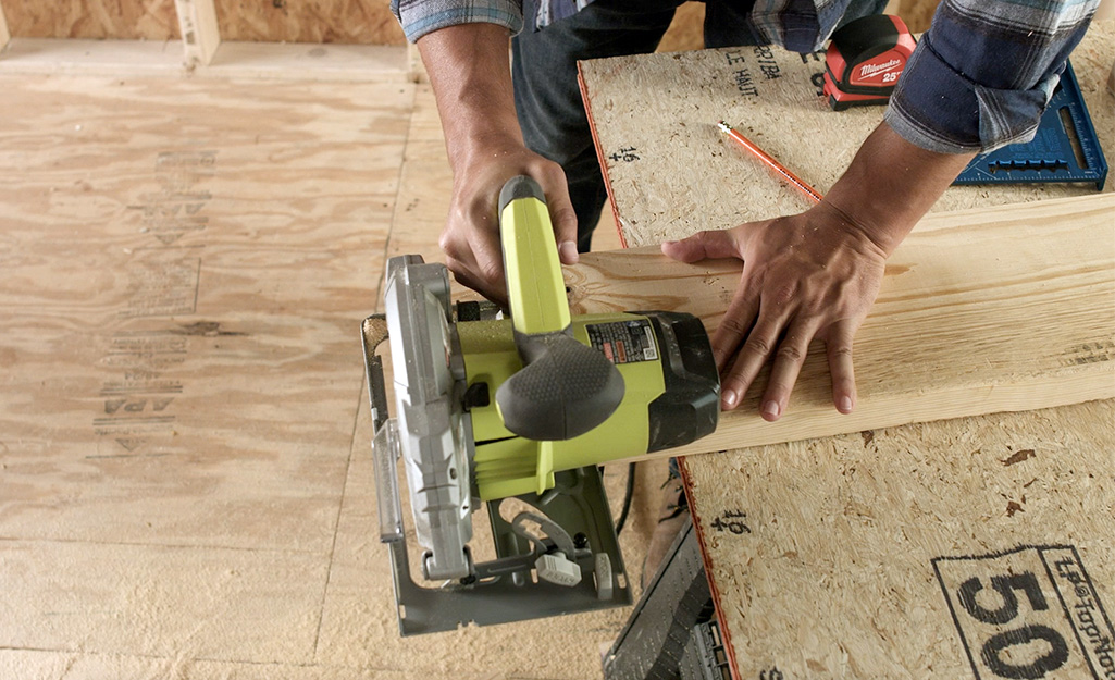 A person cutting lumber to make a door frame header.