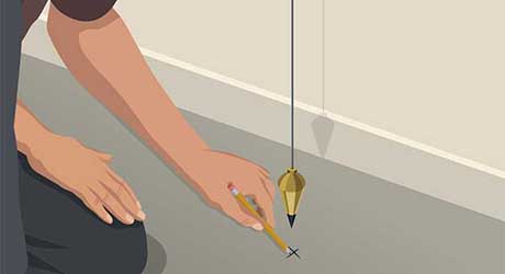 A person using a pencil to mark a spot on the floor underneath a plumb bob A person using a pencil to mark a spot on the floor underneath a plumb bob