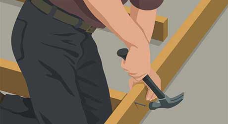 Person using a hammer to nail studs in place Person using a hammer to nail studs in place
