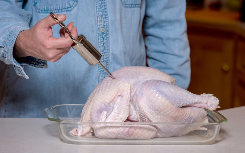 A person injecting a turkey to prepare it for the turkey fryer. A person injecting a turkey to prepare it for the turkey fryer.