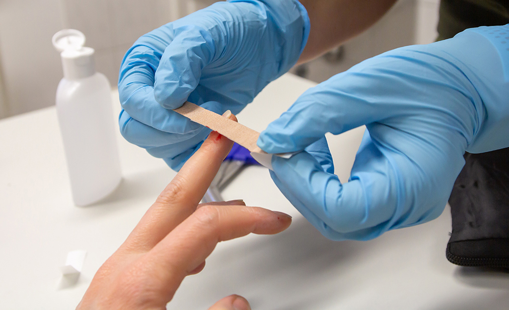 A person puts a small bandage over a finger splinter.