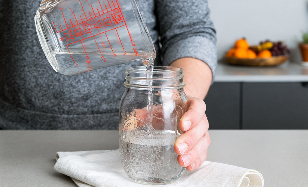 Someone pouring vinegar into a jar.