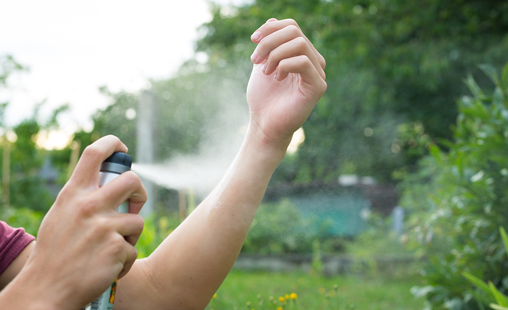 A person sprays mosquito repellent on his wrist.