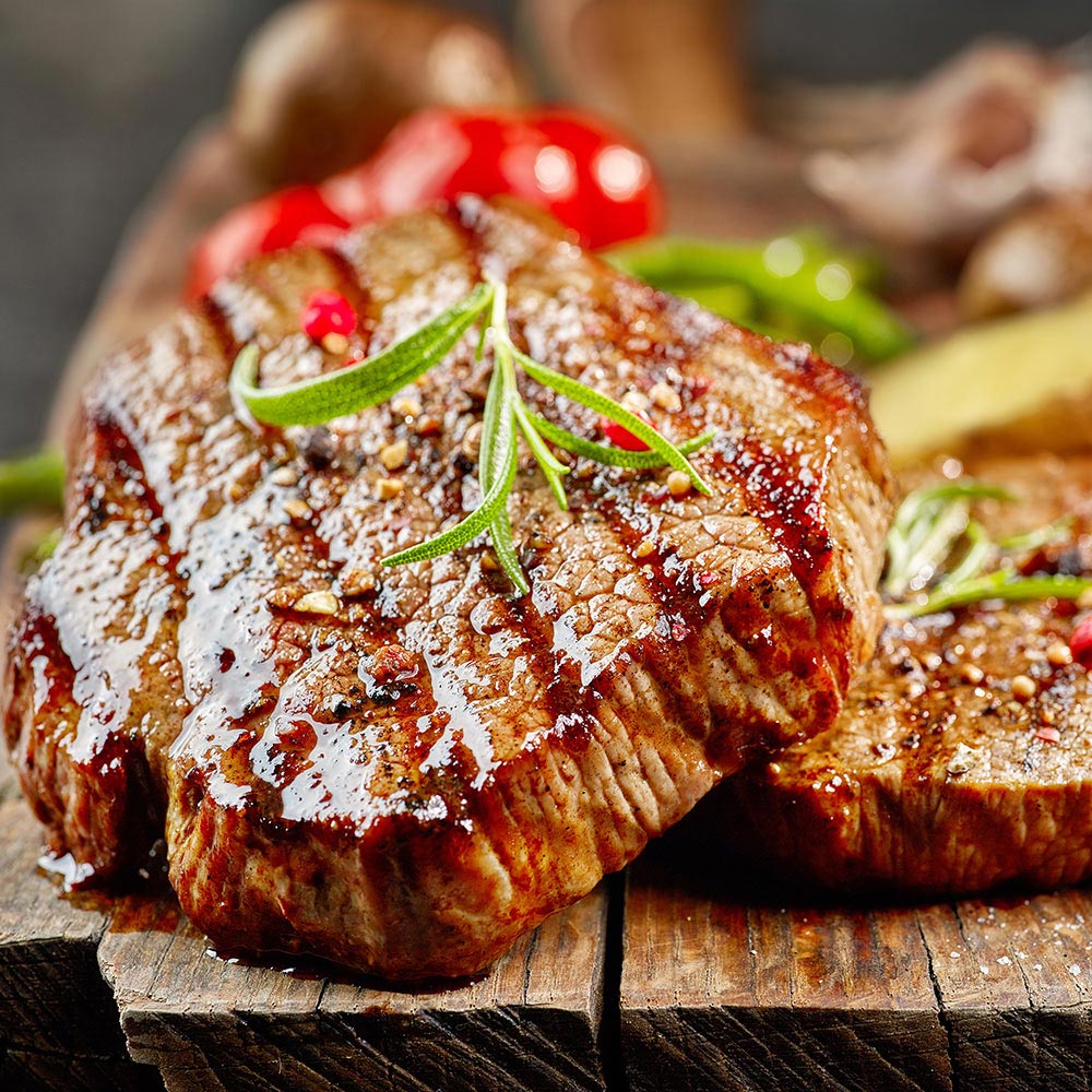 A grilled steak rests on a cutting board.