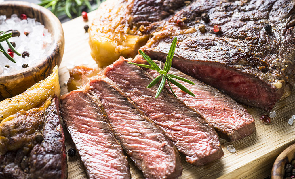 Freshly sliced grilled steak on a cutting board.