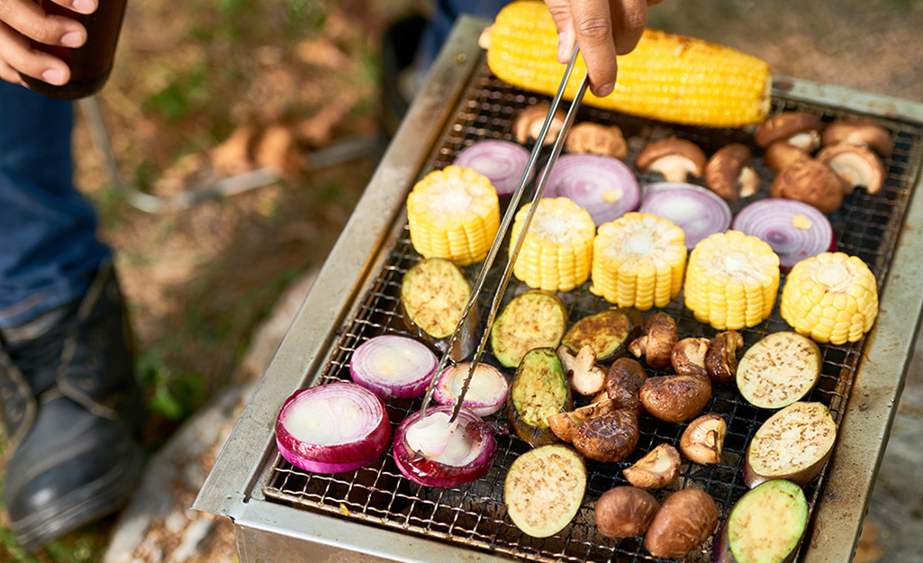 Sliced corn, eggplant and other vegetables cook on a grill. Sliced corn, eggplant and other vegetables cook on a grill.