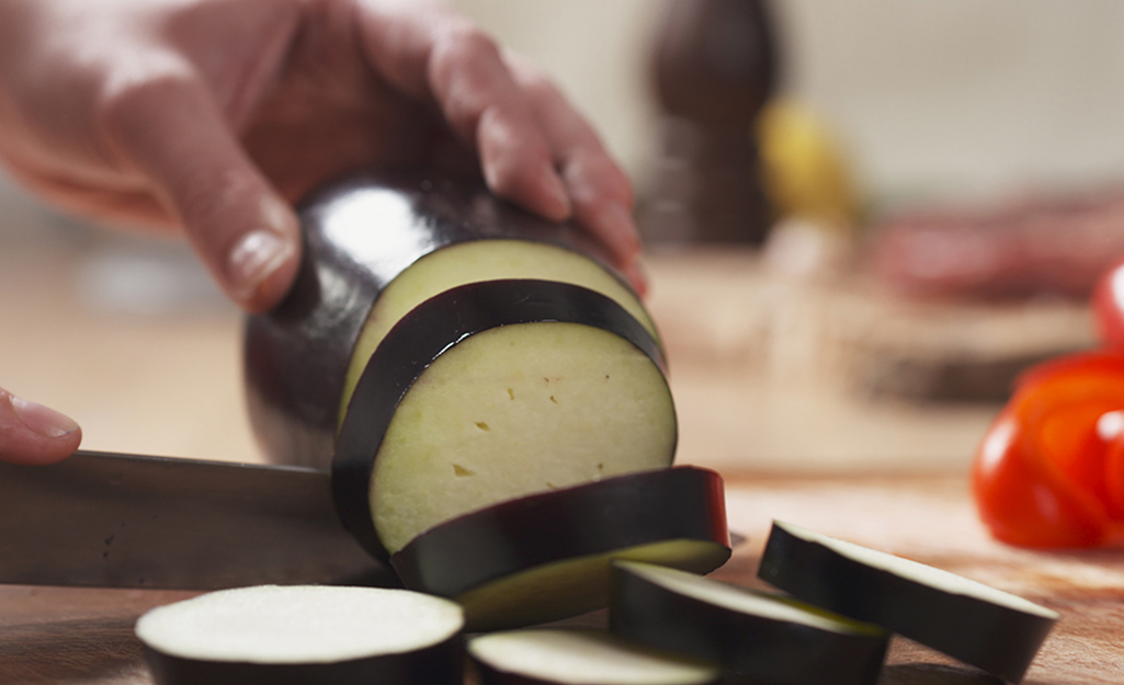 A person slices zucchini with a knife. A person slices zucchini with a knife.