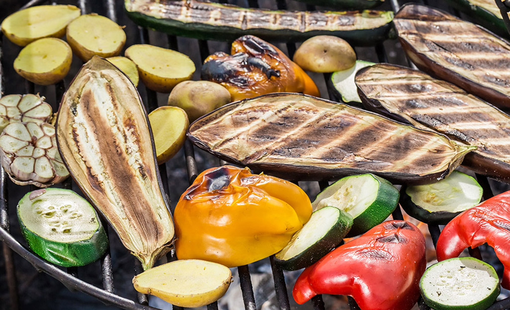 Eggplant, peppers and other vegetables cook on a grill. Eggplant, peppers and other vegetables cook on a grill.