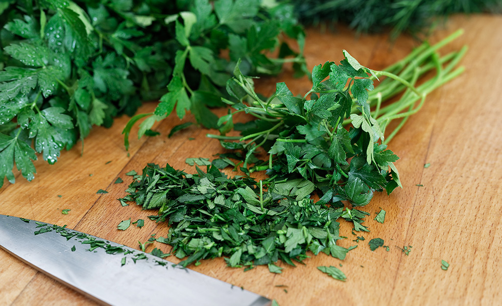 Parsley and a knife on a cutting board.