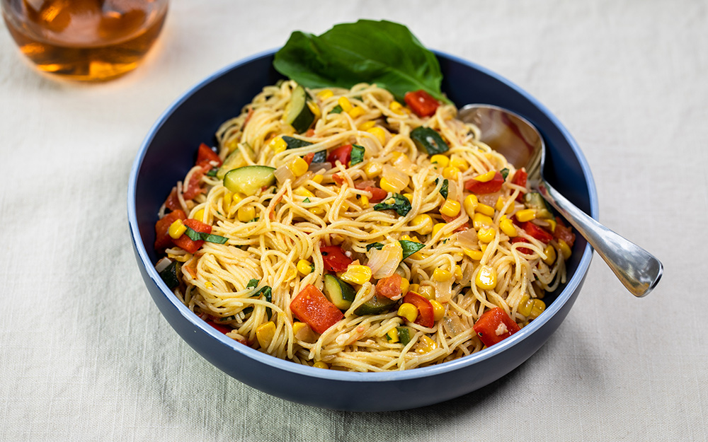 Bowl of pasta with summer vegetables and basil