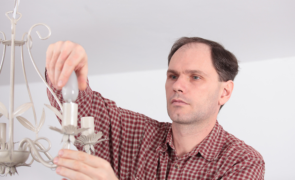 A person screws light bulbs into a chandelier.
