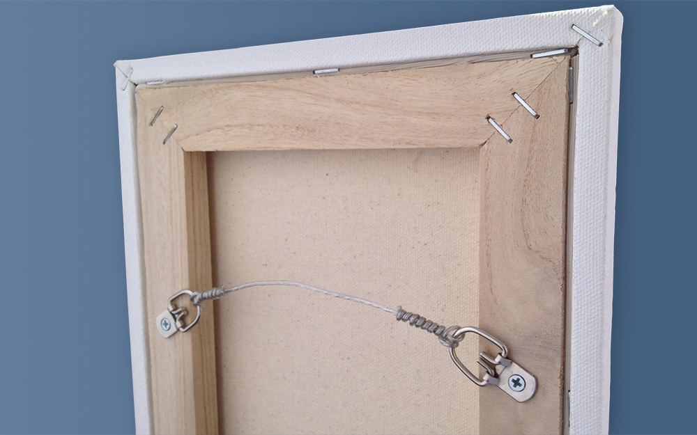 Picture wire strung between two D-rings attached to the back of a picture frame.