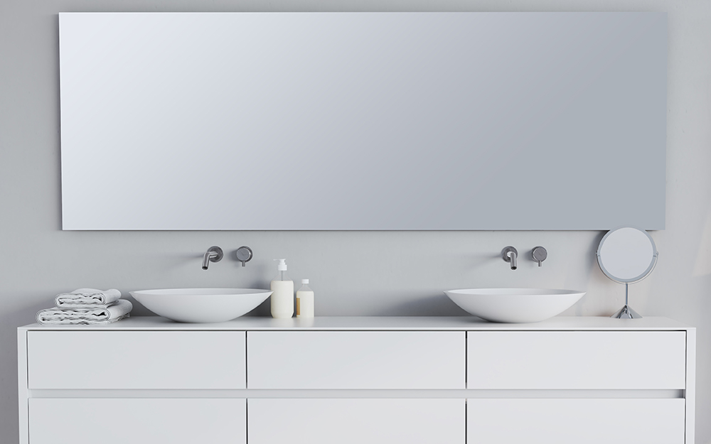 A large frameless mirror is hung on a bathroom wall behind a bathtub.