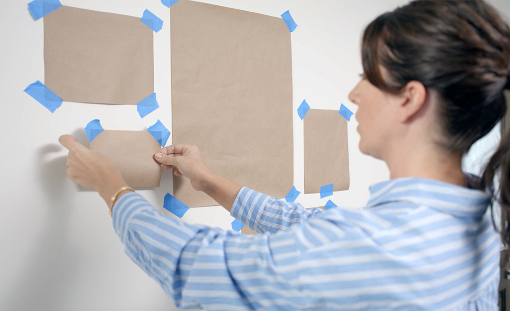 A woman uses kraft paper to create a gallery wall template.