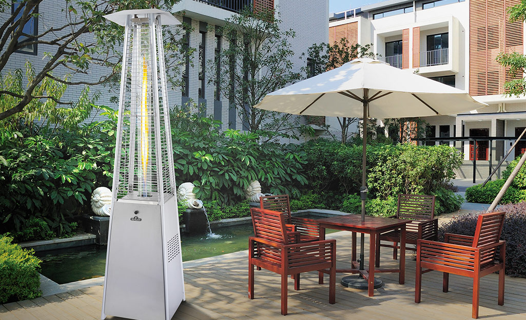 A propane patio heater outdoors next to a redwood patio set.