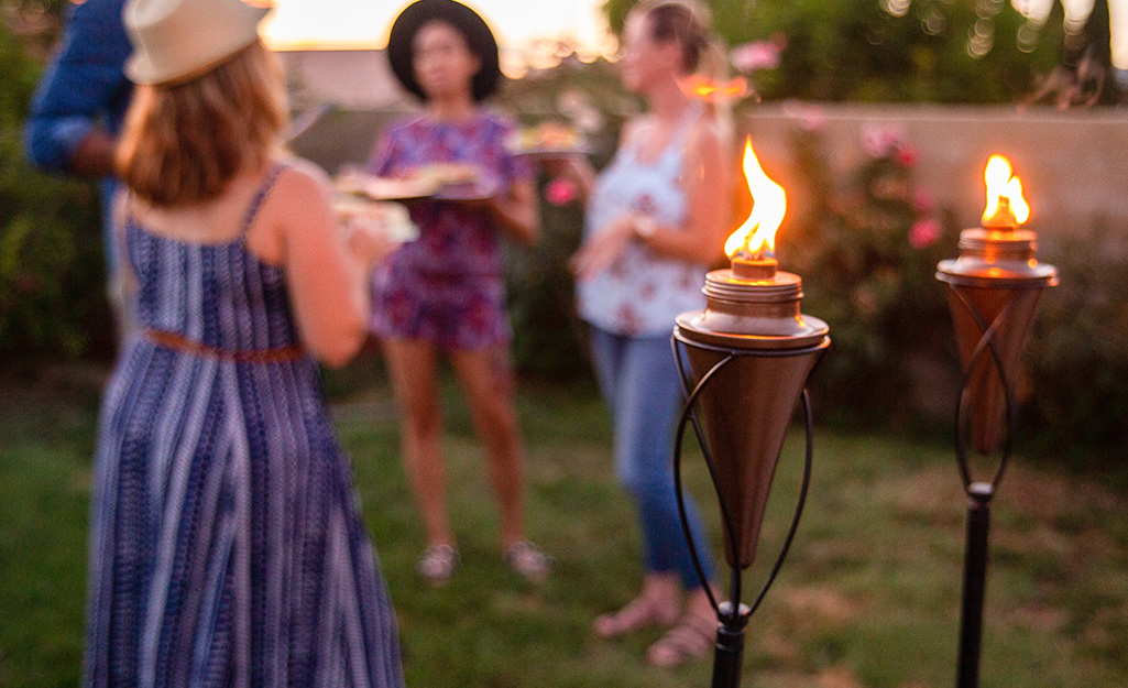A backyard gathering lit by two tiki torches.