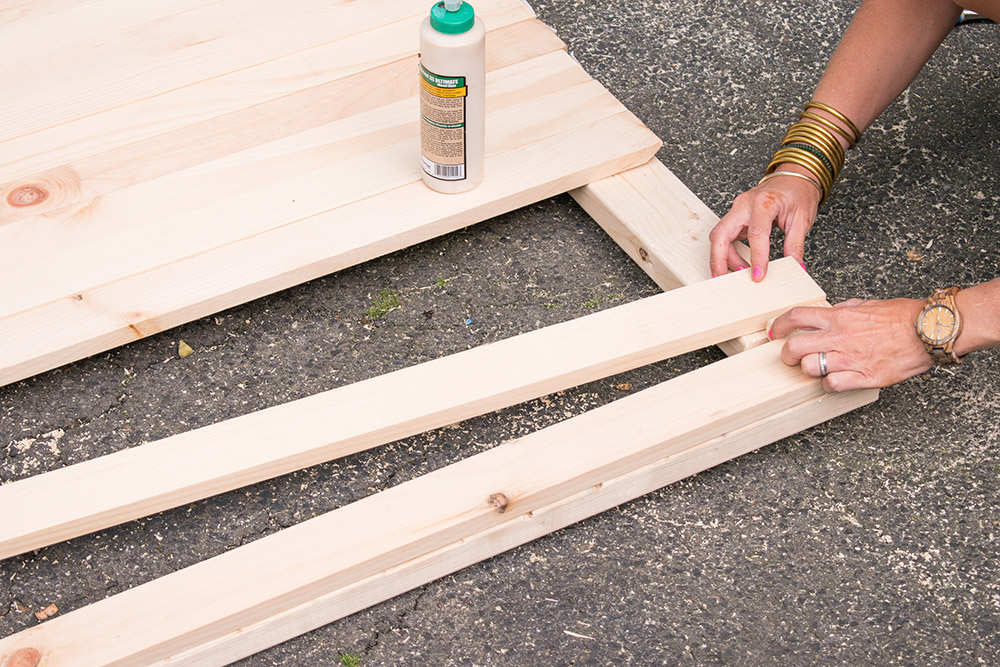 A person using wood glue to secure wood panels