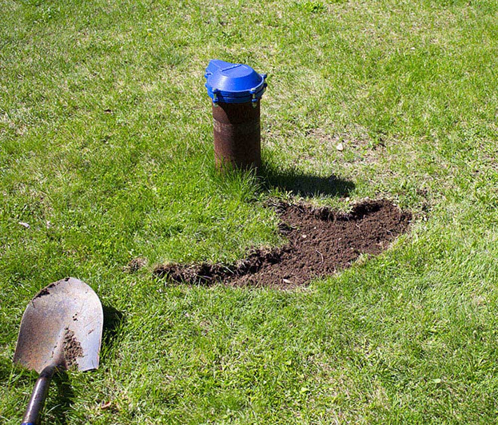A shovel next to a grass area with exposed soil.