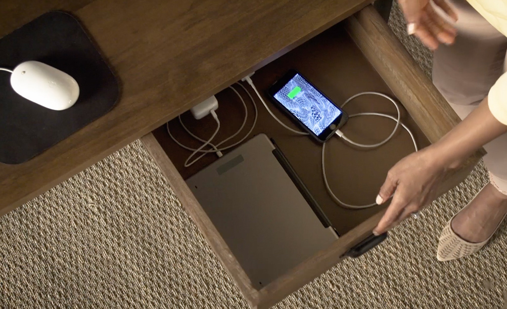 A charging station for a smartphone and computer inside a desk drawer.  