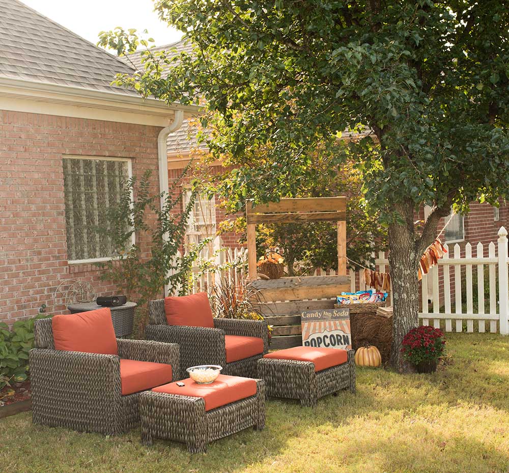 A backyard ready for a Fall movie night with outdoor seating and a concession stand.